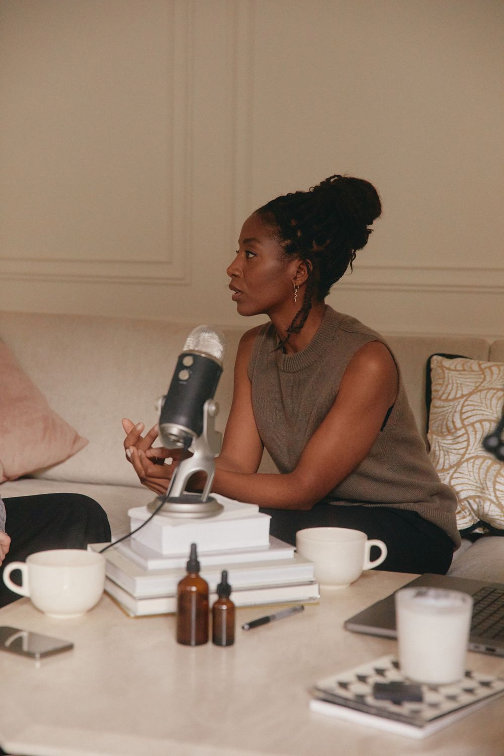 A woman speaking into a podcast microphone at home